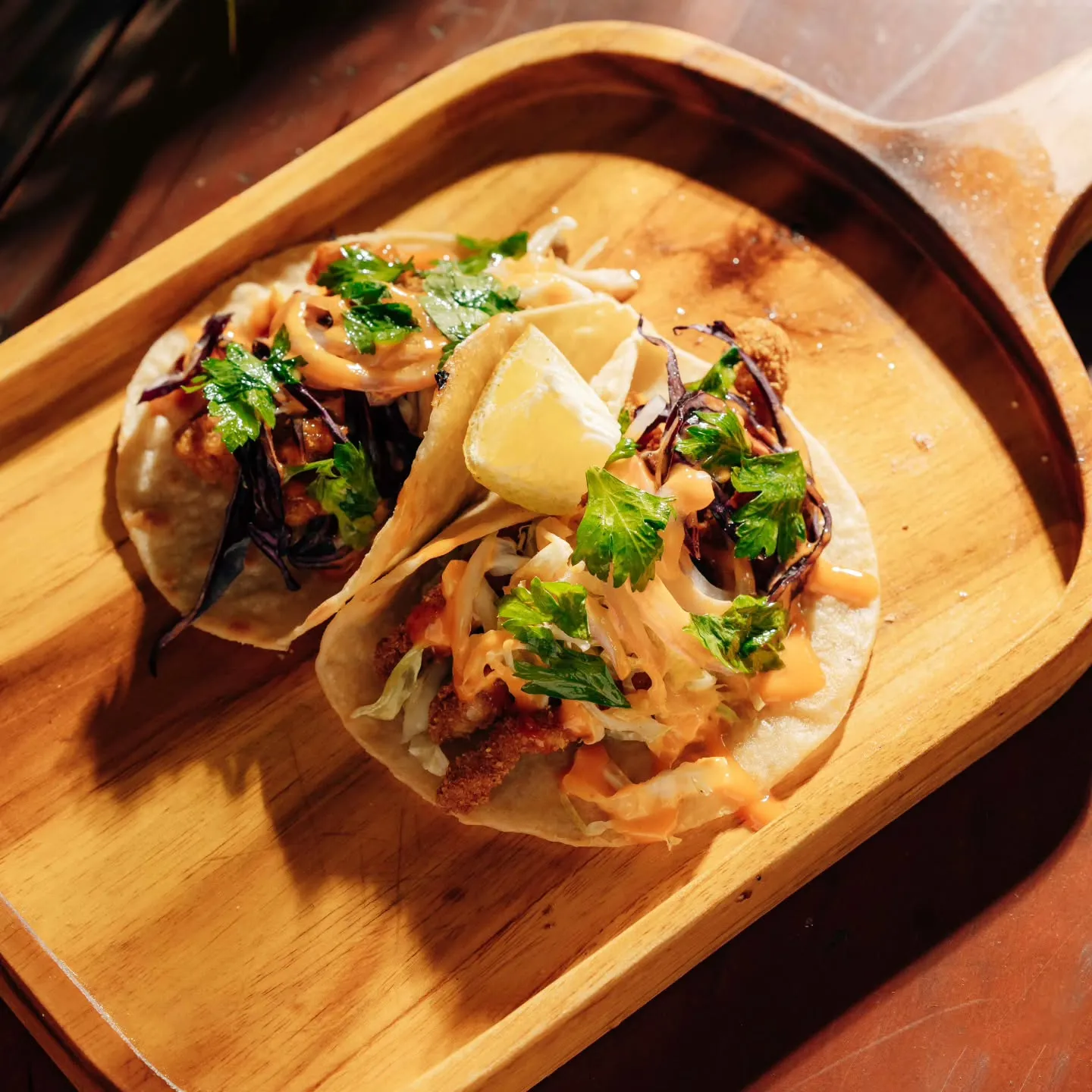 A folded taco with lime on a serving paddle
